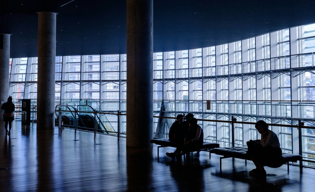 Visitors resting inside a glass-walled Tokyo museum